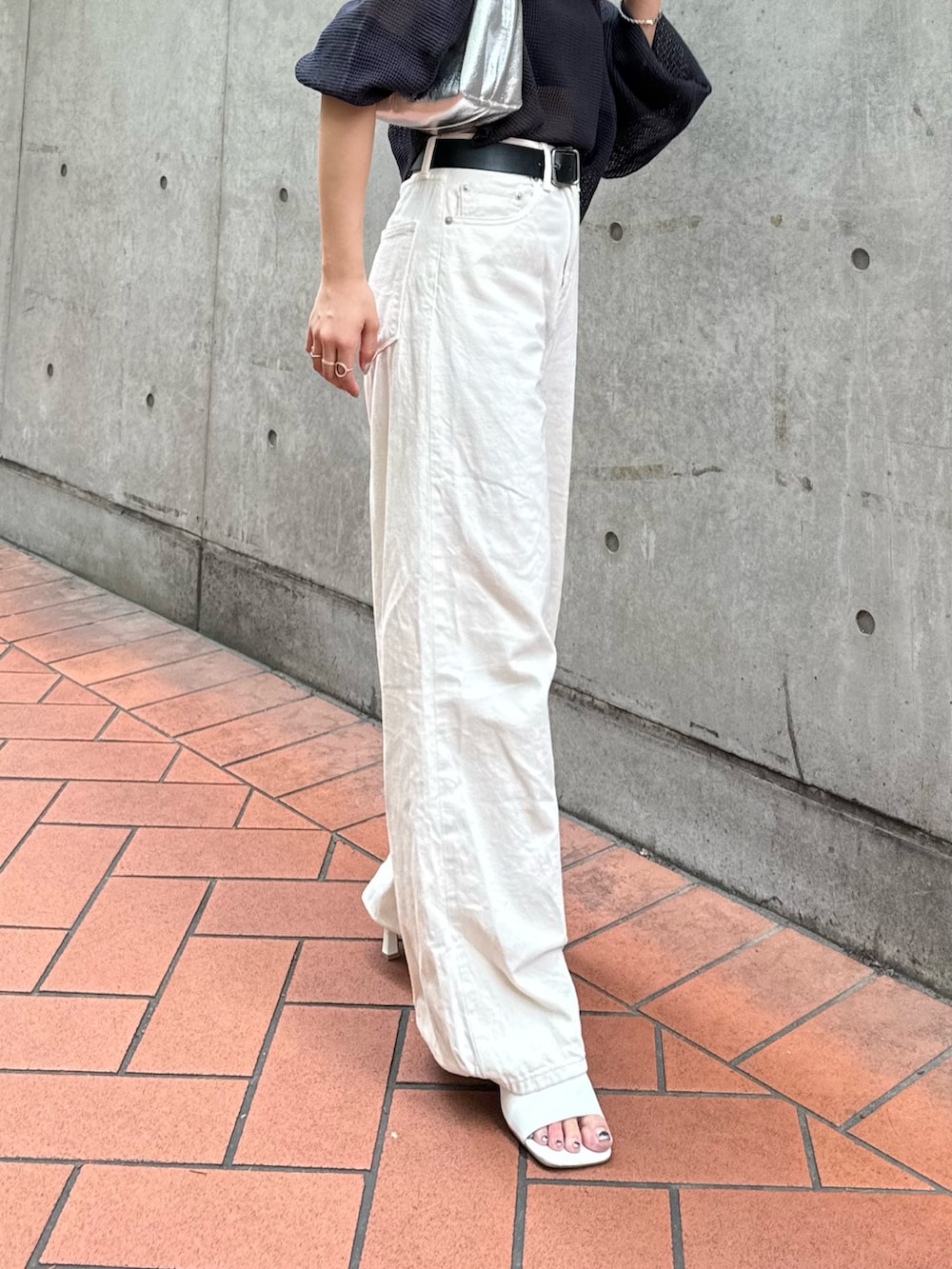 シルバー系のハンドバッグ、ホワイト系のデニムパンツ、グレー系のTシャツ/カットソーを着用したレディースの夏コーディネートの3枚目の写真