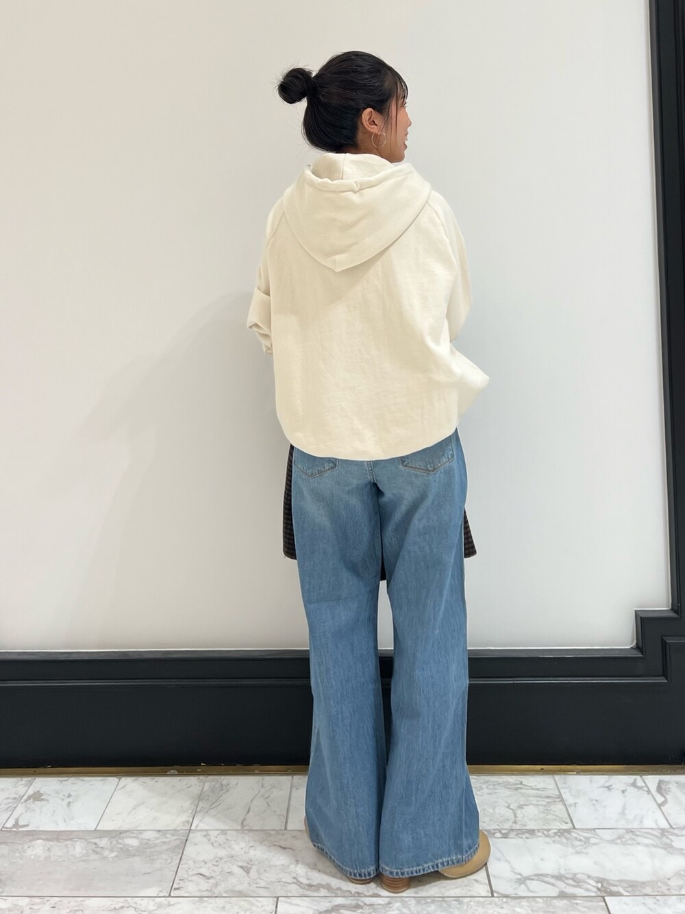 ホワイト系のパーカー、ブルー系のデニムパンツ、ベージュ系のブーツを着用したレディースの冬コーディネートの4枚目の写真