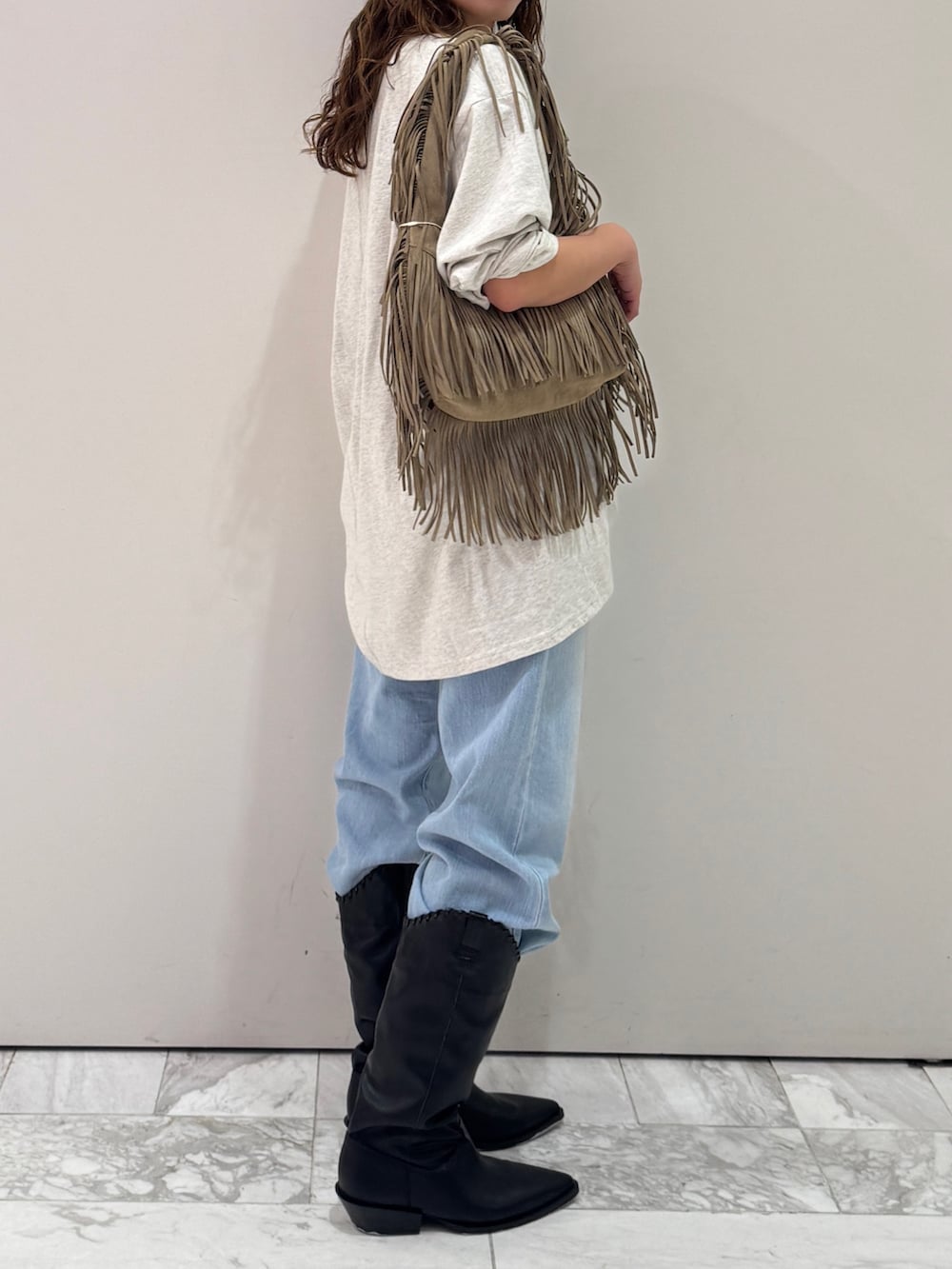 グレー系のTシャツ/カットソー、ベージュ系のハンドバッグ、ブルー系のデニムパンツを着用したレディースの春コーディネートの7枚目の写真