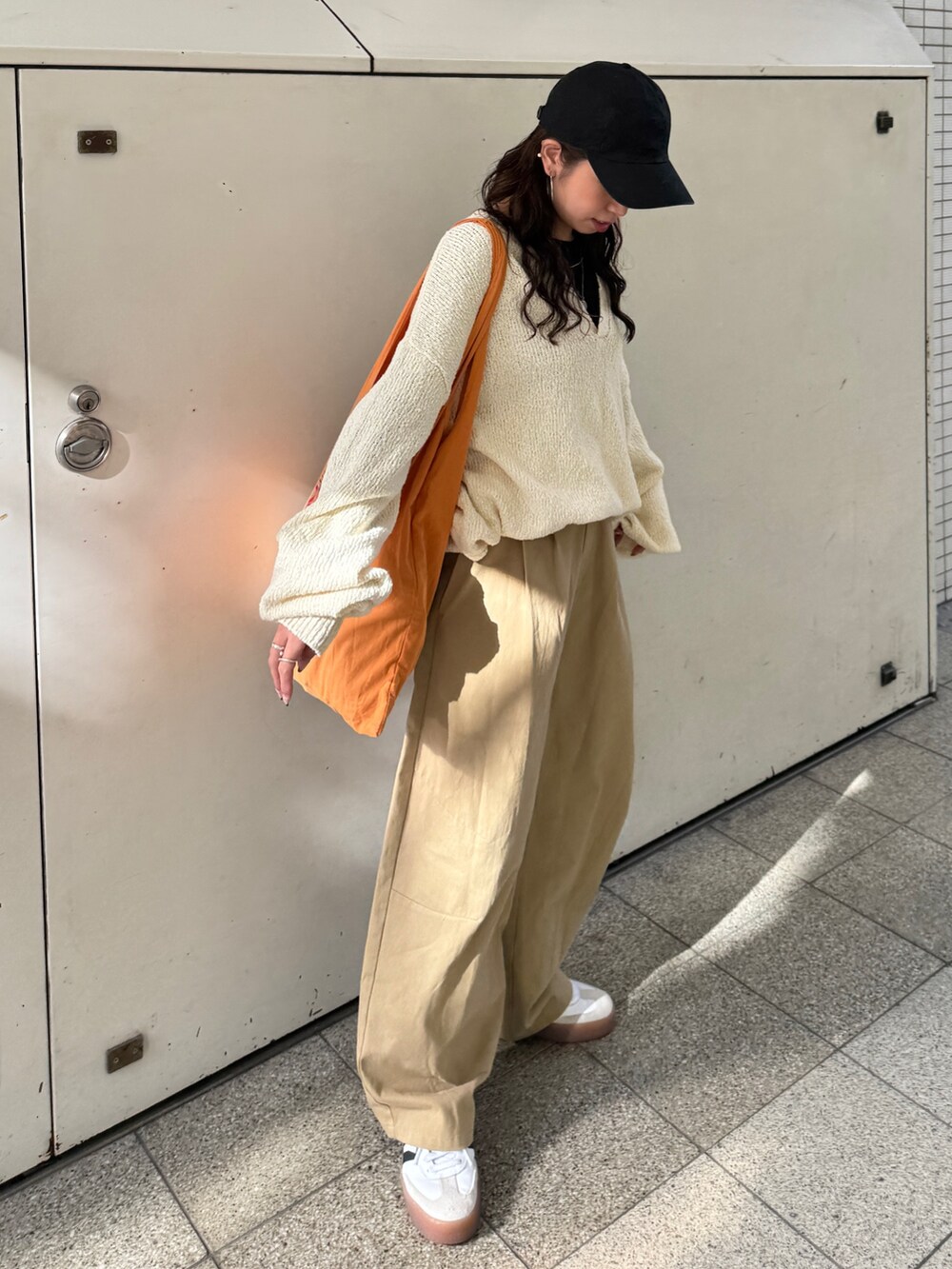 ベージュ系のチノパンツ、ホワイト系のニット/セーター、オレンジ系のエコバッグ/サブバッグを着用したレディースの冬コーディネートの5枚目の写真