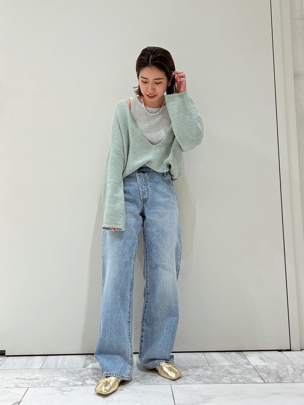 ブルー系のデニムパンツ、イエロー系のパンプス、グリーン系のニット/セーターを着用したレディースの冬コーディネートの7枚目の写真