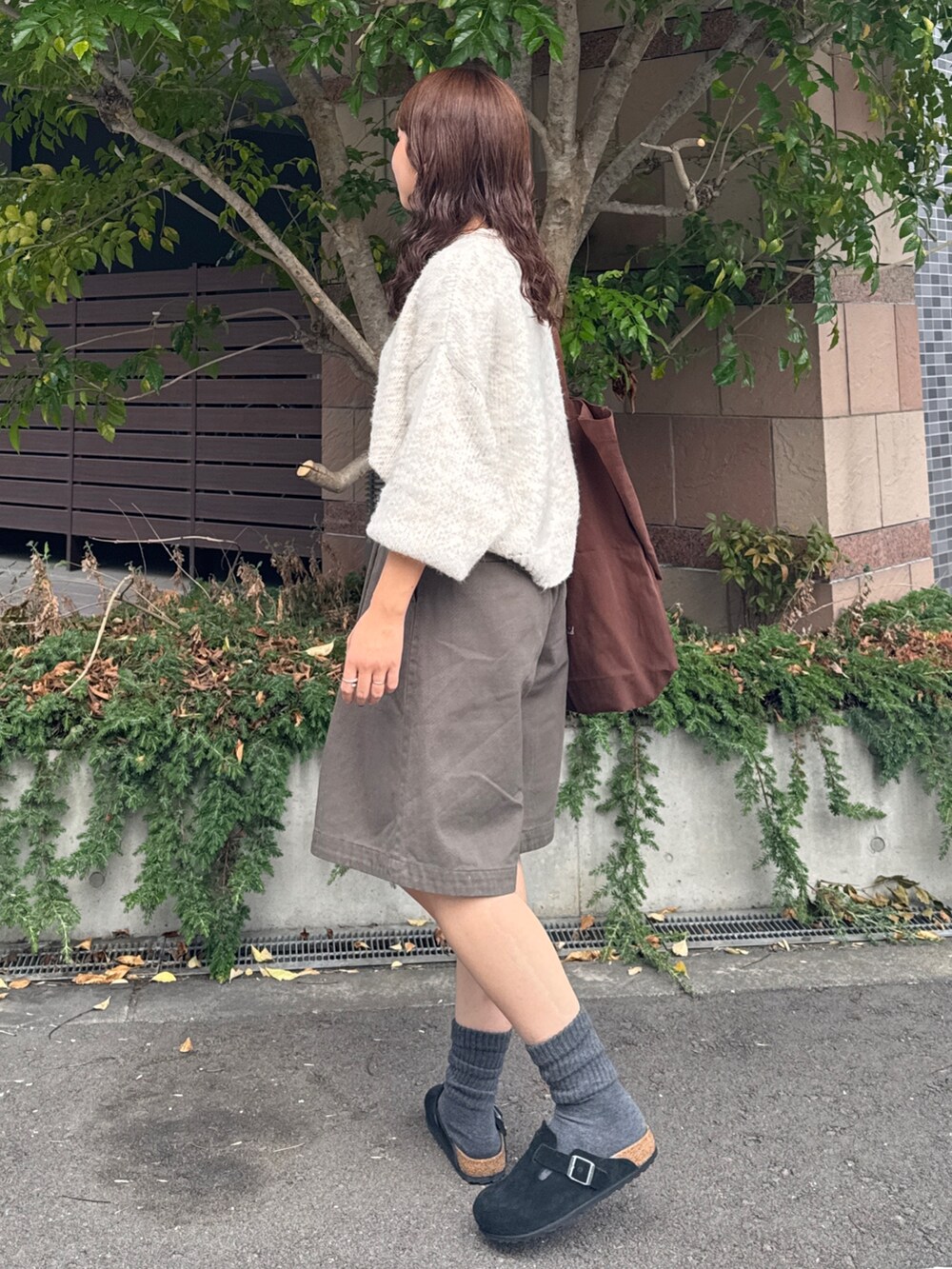 グレー系のチノパンツ、ホワイト系のニット/セーター、ブラウン系のトートバッグを着用したレディースの秋コーディネートの7枚目の写真