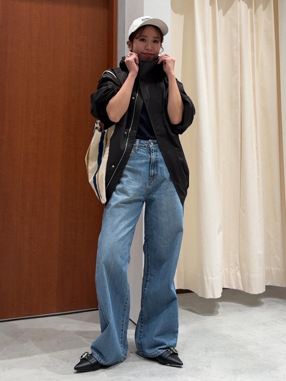 ブラック系のブルゾン、ブラック系のTシャツ/カットソー、ブルー系のデニムパンツを着用したレディースの春コーディネートの9枚目の写真