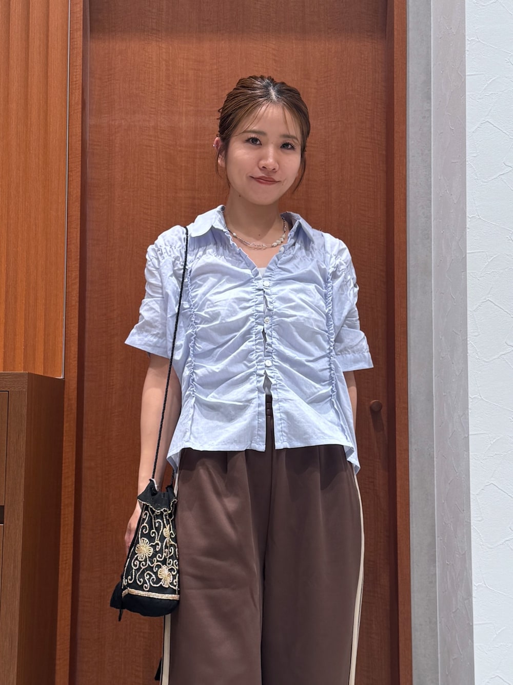ブラウン系のその他パンツ、ブルー系のシャツ/ブラウス、ブラック系のハンドバッグを着用したレディースの夏コーディネートの7枚目の写真