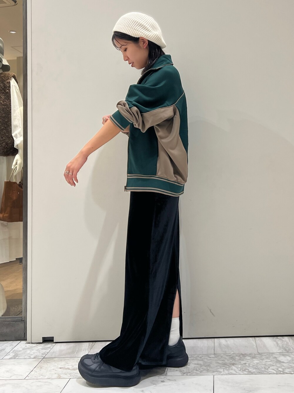 ブラック系のスカート、グリーン系のブルゾン、ホワイト系のキャミソールを着用したレディースの秋コーディネートの8枚目の写真