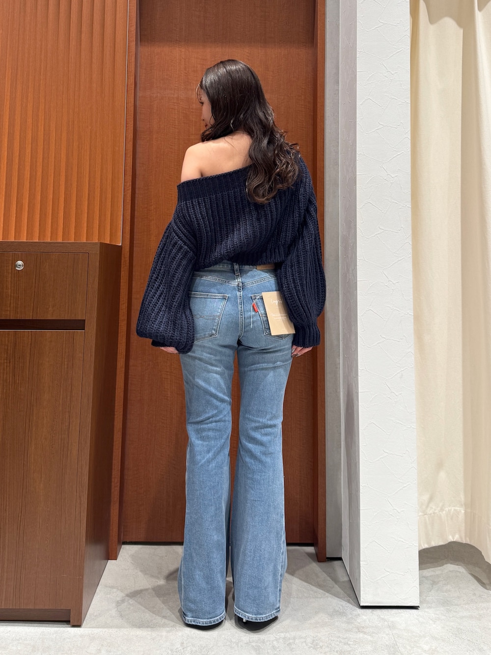 ブルー系のニット/セーター、ブルー系のデニムパンツ、シルバー系のパンプスを着用したレディースの秋コーディネートの4枚目の写真