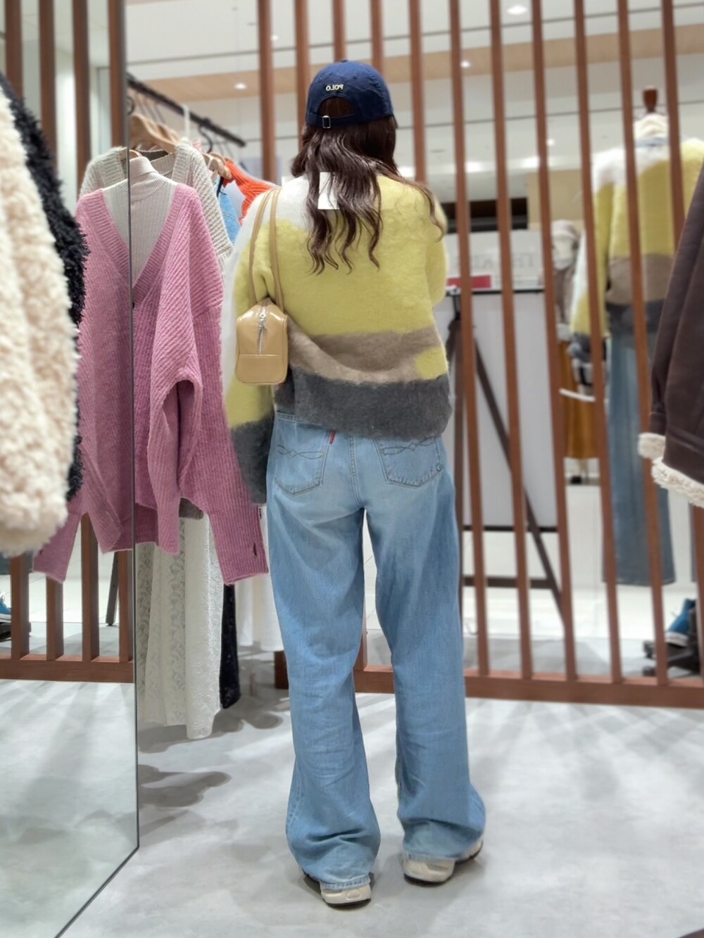 グリーン系のニット/セーター、ブルー系のデニムパンツ、ベージュ系のハンドバッグを着用したレディースの秋コーディネートの6枚目の写真