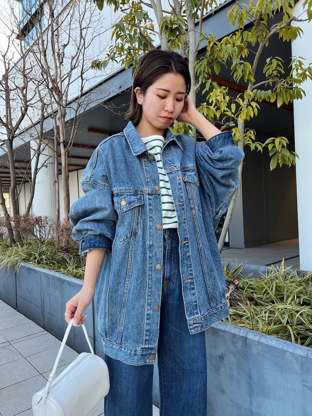 ブルー系のデニムパンツ、ホワイト系のハンドバッグ、ブルー系のデニムジャケットを着用したレディースの冬コーディネートの7枚目の写真