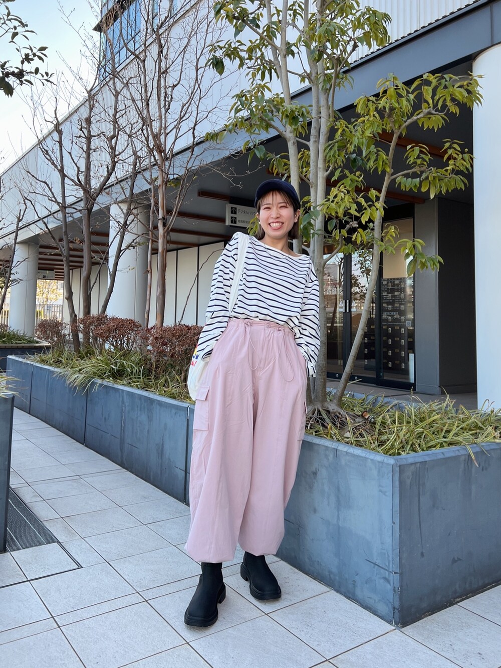 ピンク系のカーゴパンツ、ホワイト系のエコバッグ/サブバッグ、ブルー系のTシャツ/カットソーを着用したレディースの冬コーディネートの3枚目の写真