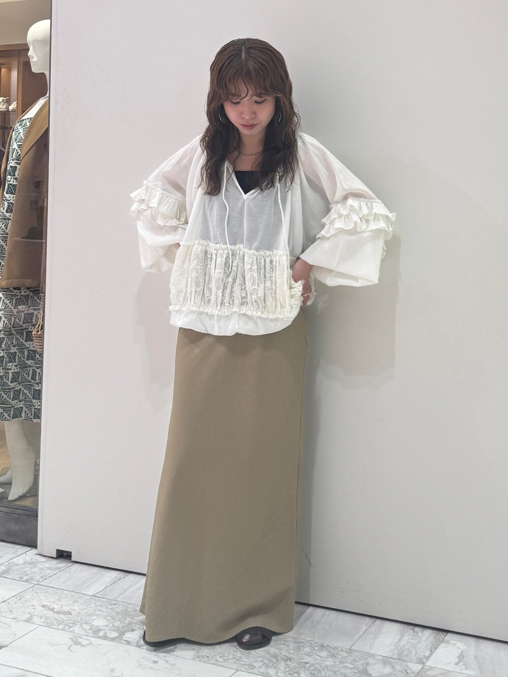 ベージュ系のスカート、ホワイト系のシャツ/ブラウス、ブラック系のキャミソールを着用したレディースの春コーディネートの2枚目の写真