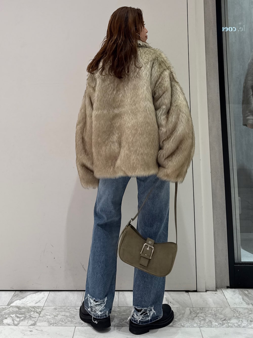 ベージュ系のダウンジャケット/コート、グリーン系のハンドバッグ、ブルー系のデニムパンツを着用したレディースの冬コーディネートの4枚目の写真