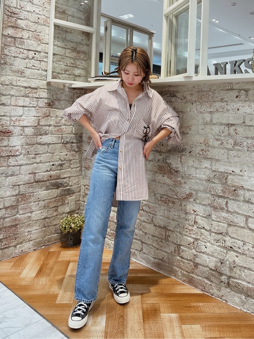 ブルー系のデニムパンツ、ブラウン系のシャツ/ブラウスを着用したレディースの夏コーディネートの2枚目の写真