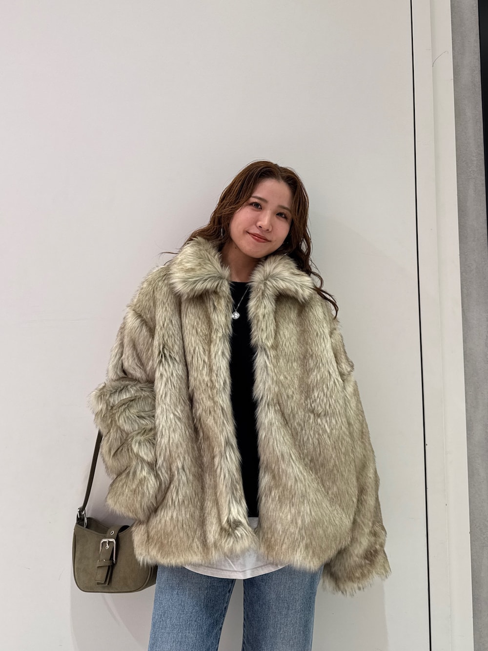 ベージュ系のダウンジャケット/コート、グリーン系のハンドバッグ、ブルー系のデニムパンツを着用したレディースの冬コーディネートの7枚目の写真