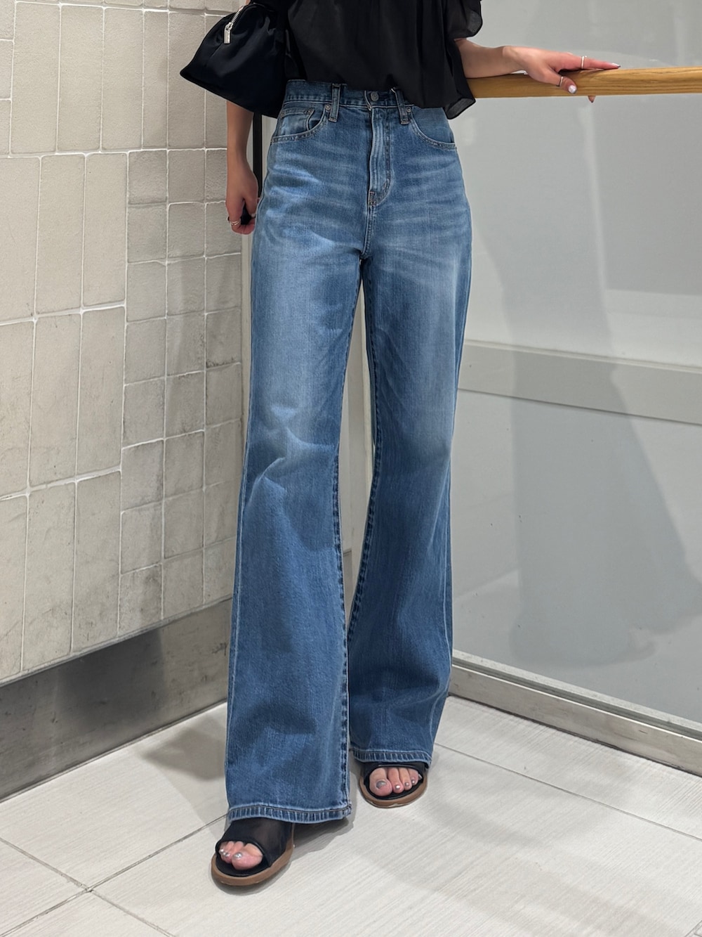 ブルー系のデニムパンツ、ブラック系のシャツ/ブラウス、ブラック系のハンドバッグを着用したレディースの春コーディネートの3枚目の写真