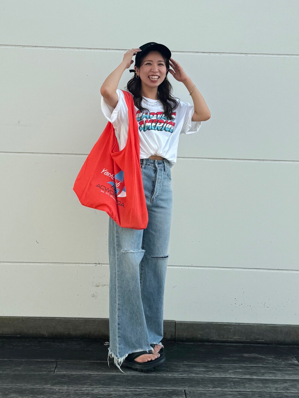 ブルー系のデニムパンツ、ホワイト系のTシャツ/カットソー、オレンジ系のエコバッグ/サブバッグを着用したレディースの夏コーディネートの2枚目の写真