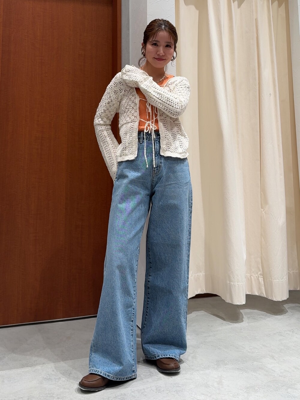 ブルー系のデニムパンツ、オレンジ系のタンクトップ、ホワイト系のカーディガン/ボレロを着用したレディースの春コーディネートの8枚目の写真