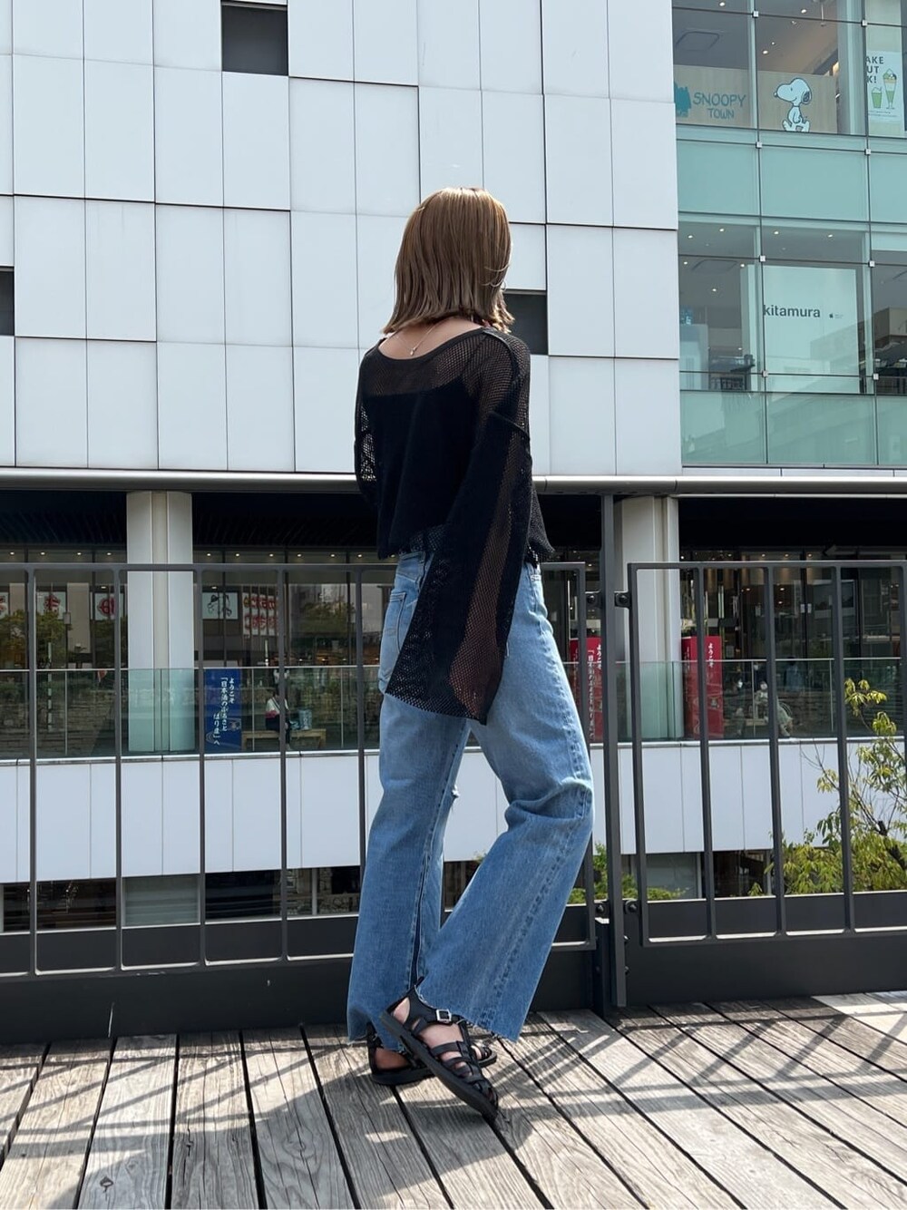 ブラック系のサンダル、ブルー系のデニムパンツ、ブラック系のTシャツ/カットソーを着用したレディースの春コーディネートの4枚目の写真
