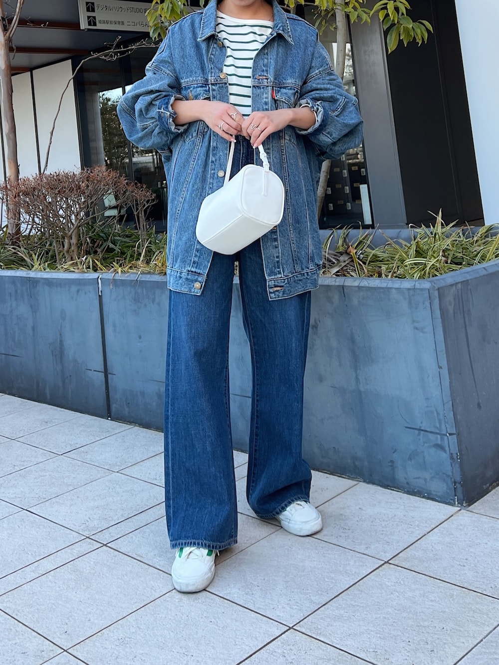 ブルー系のデニムパンツ、ホワイト系のハンドバッグ、ブルー系のデニムジャケットを着用したレディースの冬コーディネートの2枚目の写真