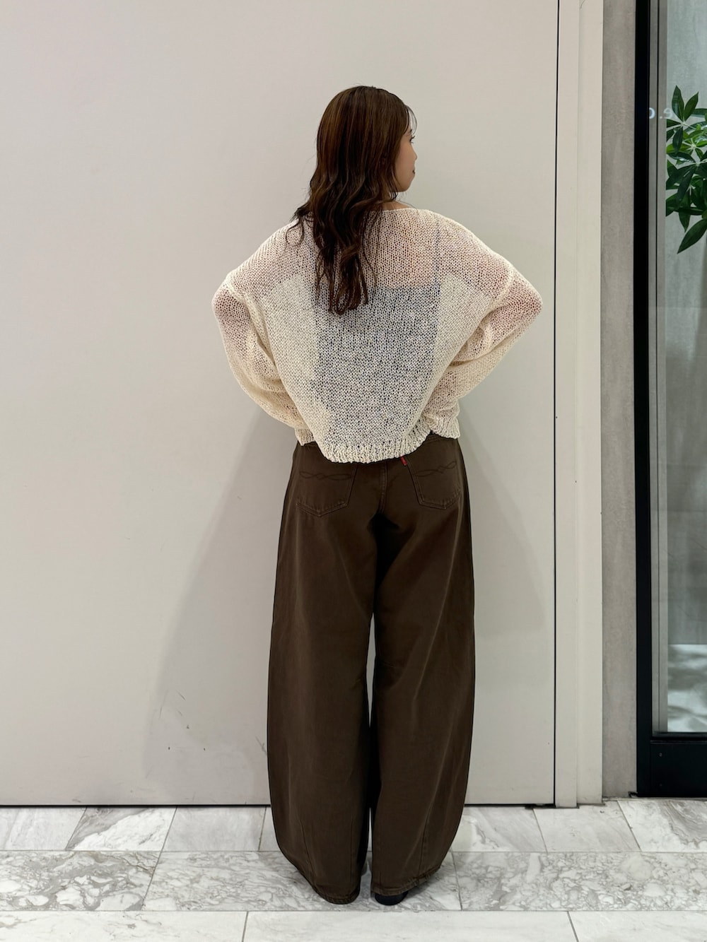 ブラウン系のデニムパンツ、ホワイト系のニット/セーター、ブラック系のサンダルを着用したレディースの秋コーディネートの5枚目の写真
