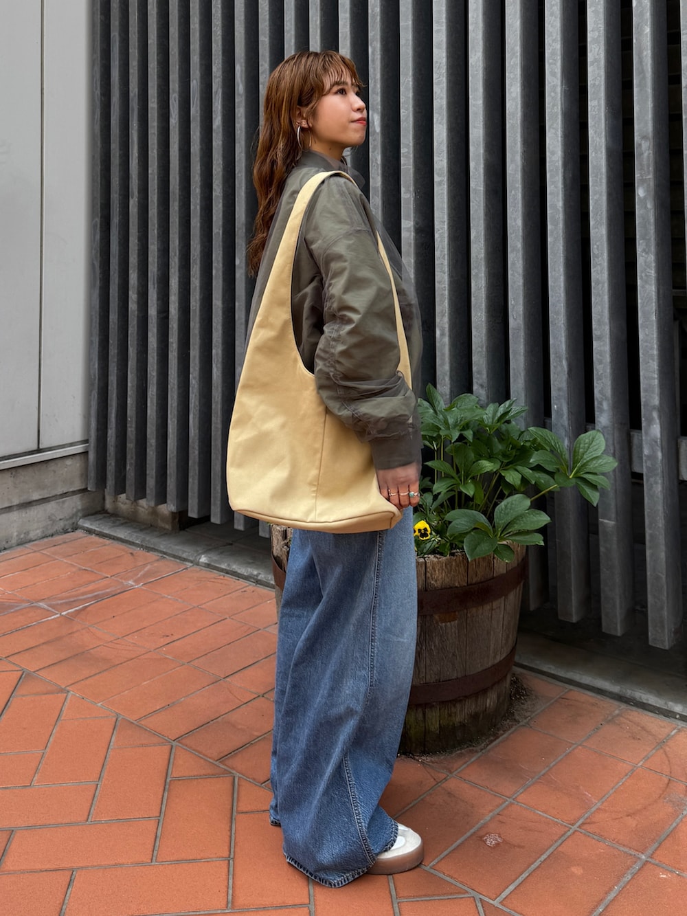 ベージュ系のトートバッグ、ホワイト系のタンクトップ、ブルー系のデニムパンツを着用したレディースの夏コーディネートの3枚目の写真