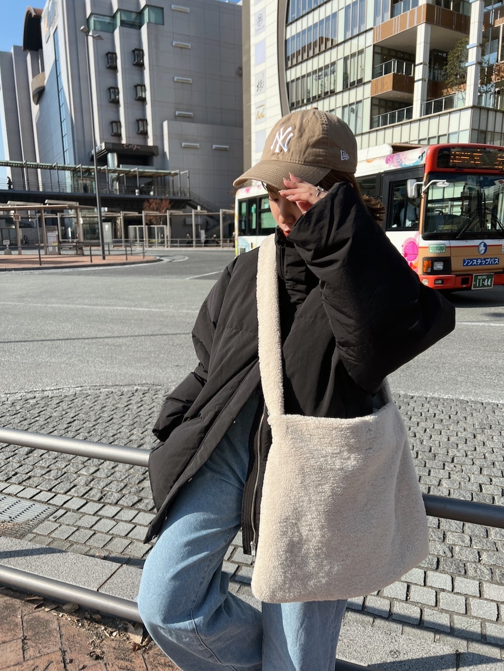 ブラック系のダウンジャケット/コート、ホワイト系のショルダーバッグ、ブルー系のデニムパンツを着用したレディースの秋コーディネートの7枚目の写真