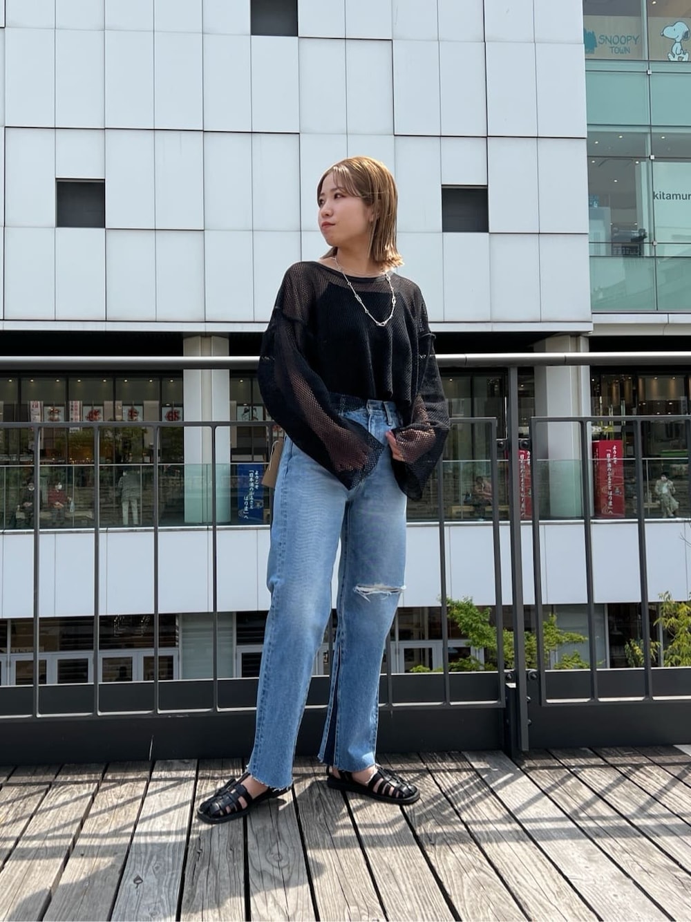ブラック系のサンダル、ブルー系のデニムパンツ、ブラック系のTシャツ/カットソーを着用したレディースの春コーディネートの5枚目の写真