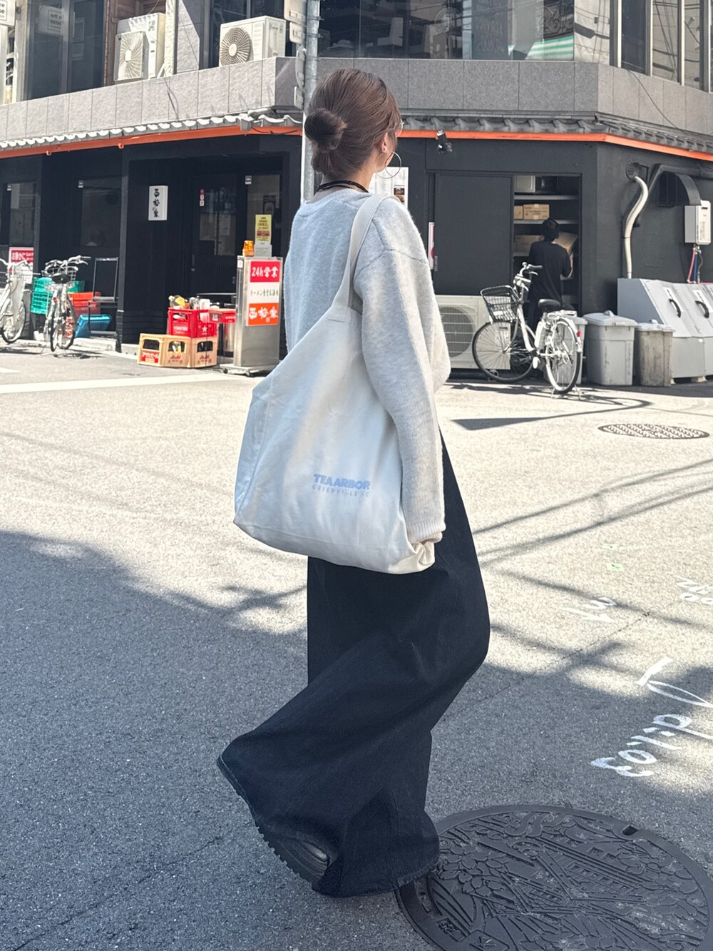 ブルー系のデニムパンツ、ホワイト系のニット/セーター、ホワイト系のトートバッグを着用したレディースの夏コーディネートの5枚目の写真