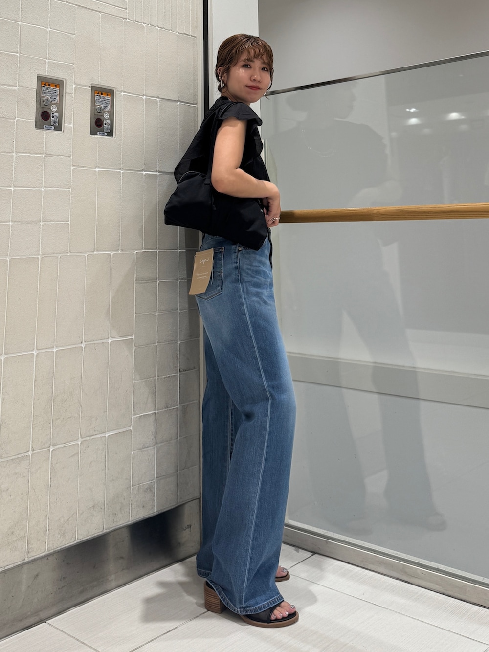 ブルー系のデニムパンツ、ブラック系のシャツ/ブラウス、ブラック系のハンドバッグを着用したレディースの春コーディネートの6枚目の写真