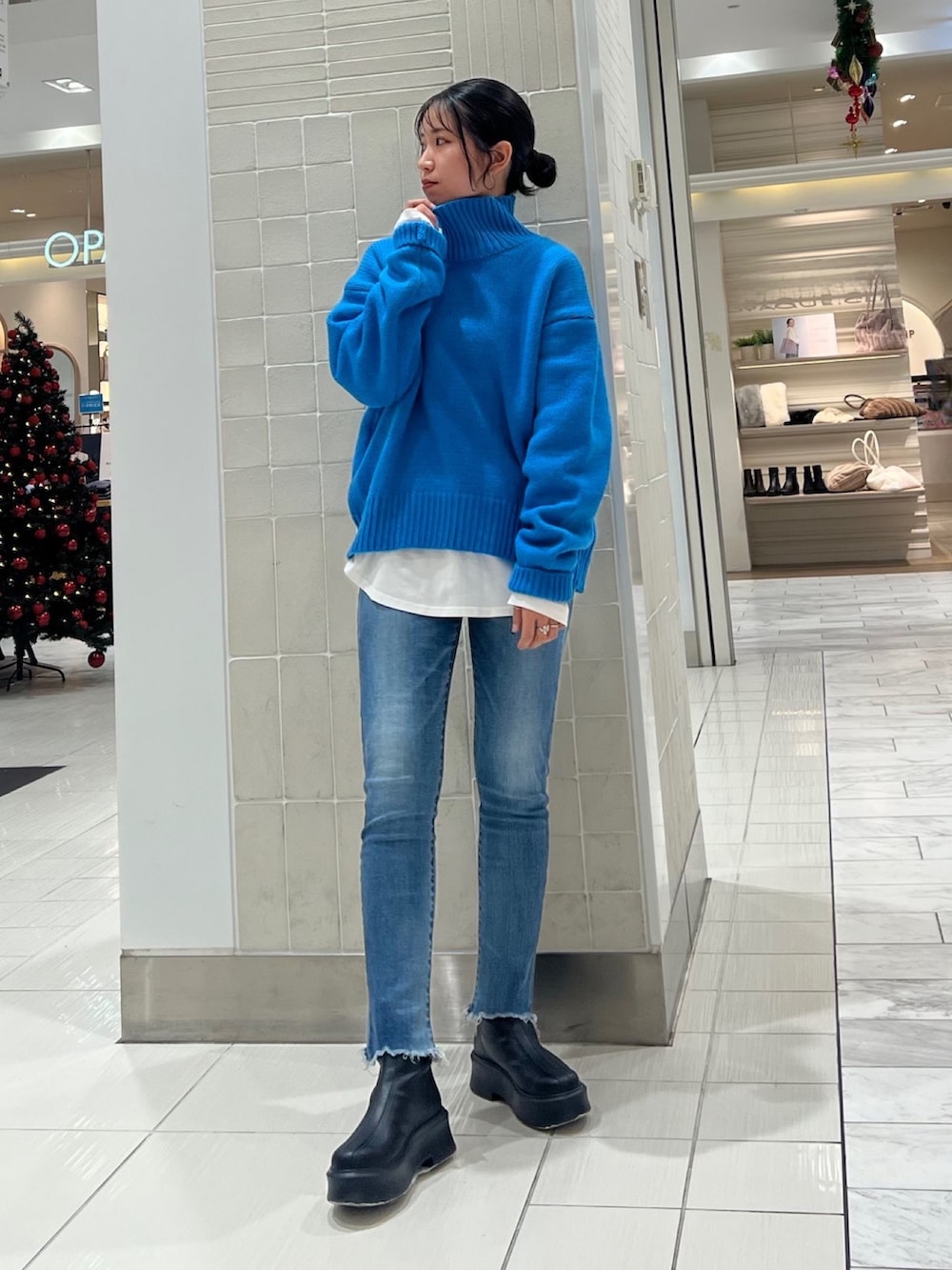 ブルー系のニット/セーター、ホワイト系のTシャツ/カットソー、ブラック系のブーツを着用したレディースの秋コーディネートの2枚目の写真