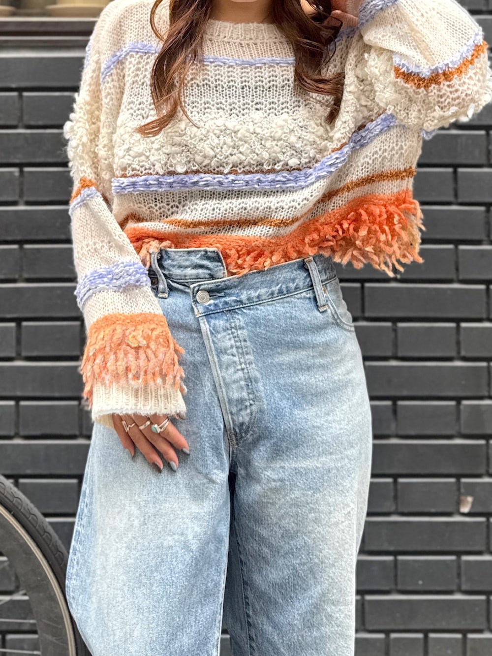 ブルー系のデニムパンツ、ホワイト系のニット/セーター、ブラック系のサンダルを着用したレディースの秋コーディネートの7枚目の写真