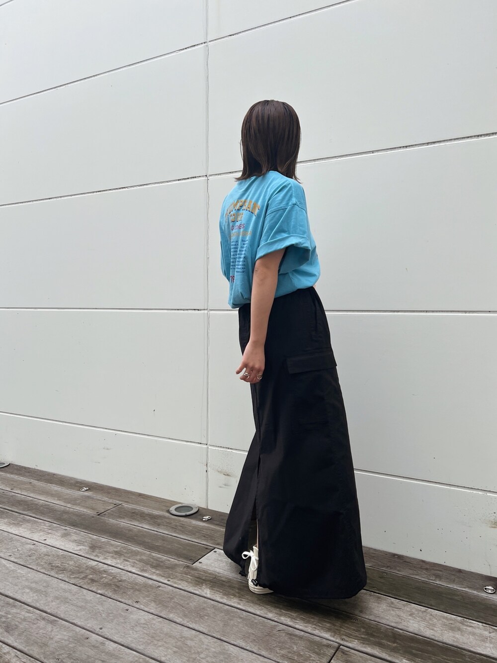 ブルー系のTシャツ/カットソー、ブラック系のスカート、ホワイト系のスニーカーを着用したレディースの春コーディネートの2枚目の写真