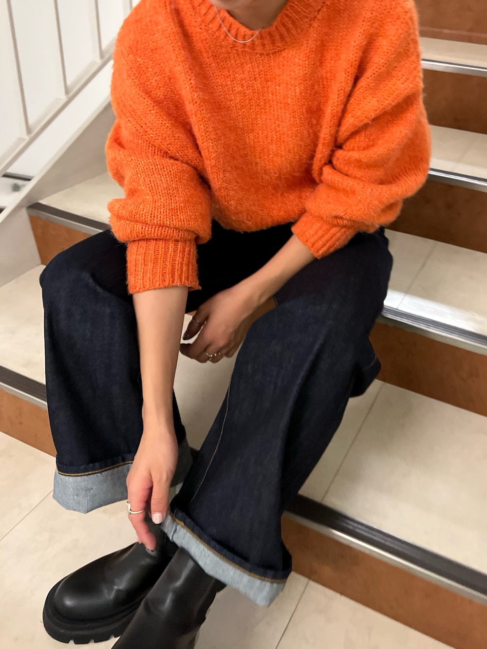 オレンジ系のニット/セーター、ブルー系のデニムパンツ、ホワイト系のダウンジャケット/コートを着用したレディースの秋コーディネートの7枚目の写真