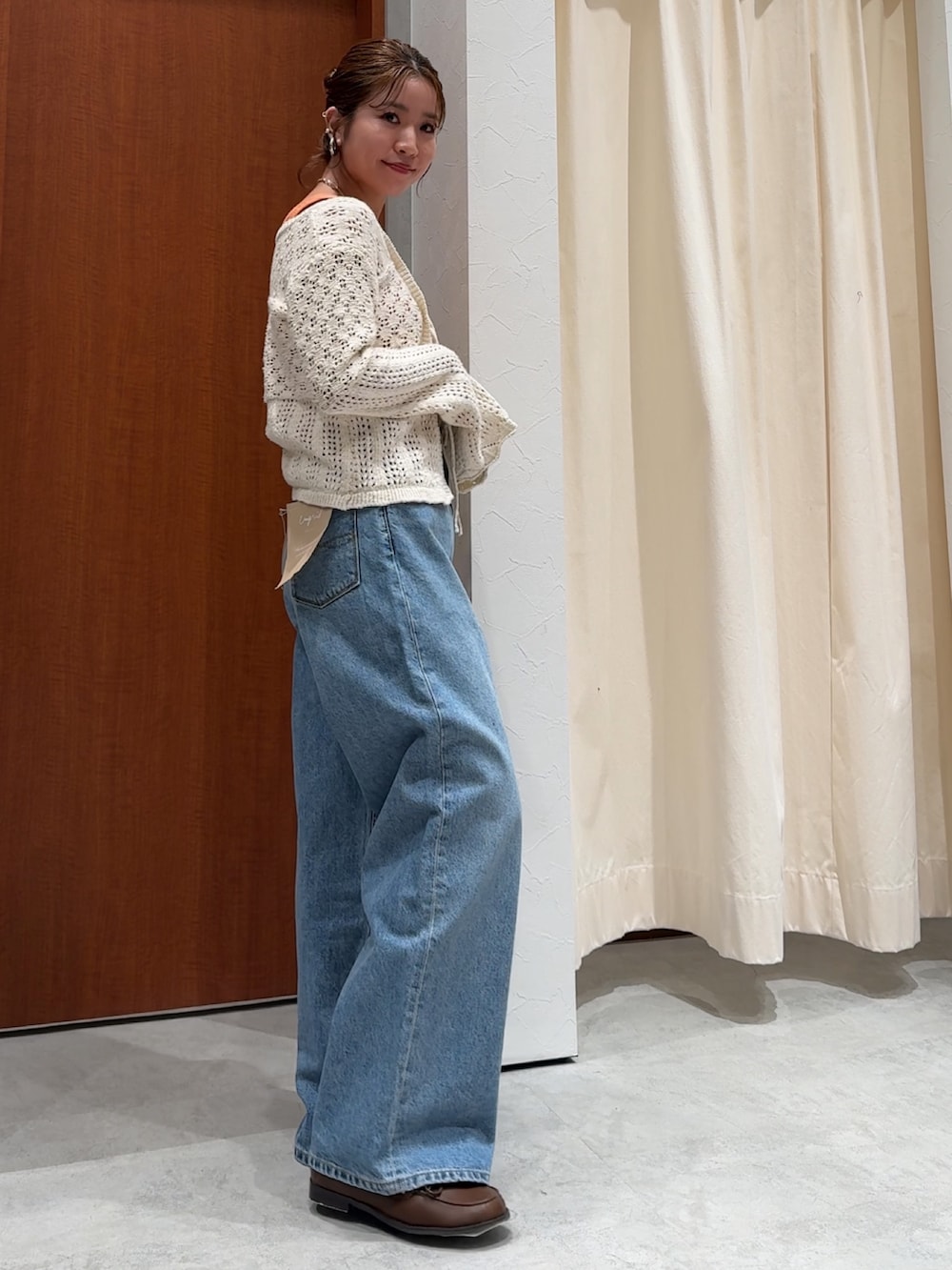 ブルー系のデニムパンツ、オレンジ系のタンクトップ、ホワイト系のカーディガン/ボレロを着用したレディースの春コーディネートの3枚目の写真