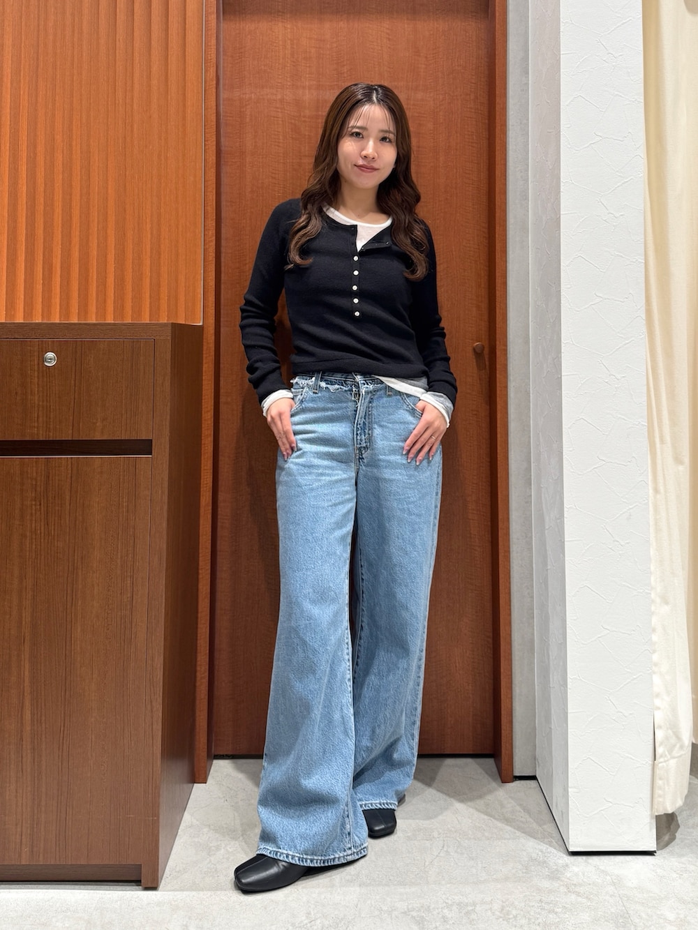 ブルー系のデニムパンツ、ブラック系のニット/セーターを着用したレディースの秋コーディネートの2枚目の写真