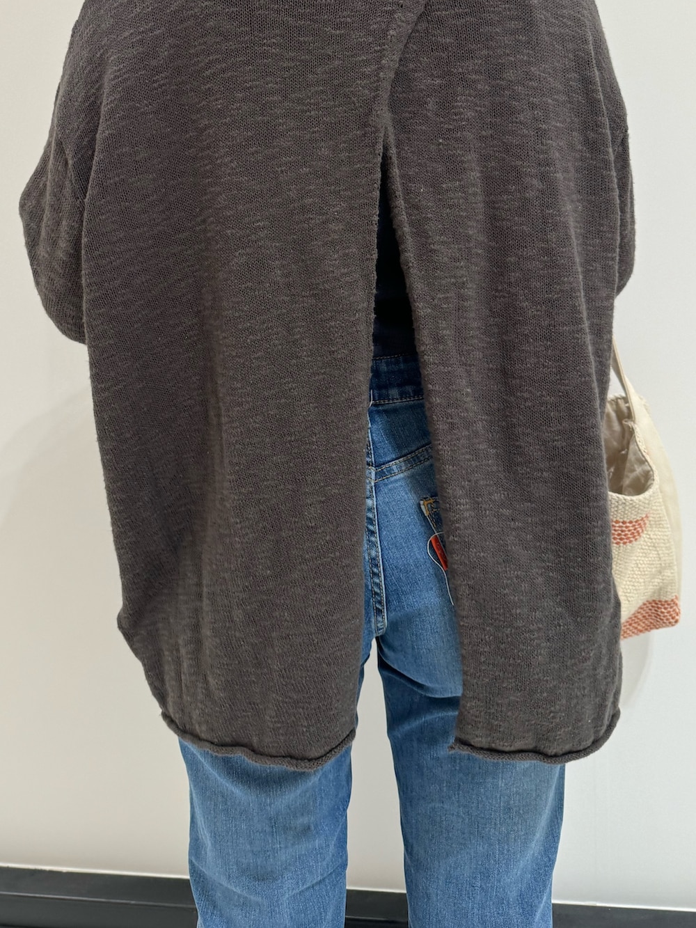 グレー系のニット/セーター、ブルー系のデニムパンツ、ブラック系のサンダルを着用したレディースの春コーディネートの7枚目の写真