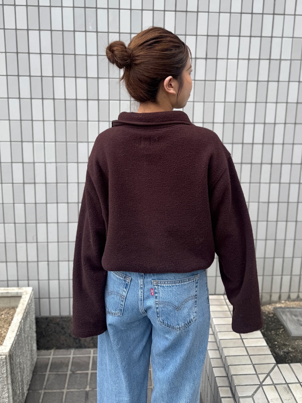 ブラウン系のパーカー、ブルー系のデニムパンツ、ブラック系のサンダルを着用したレディースの秋コーディネートの9枚目の写真