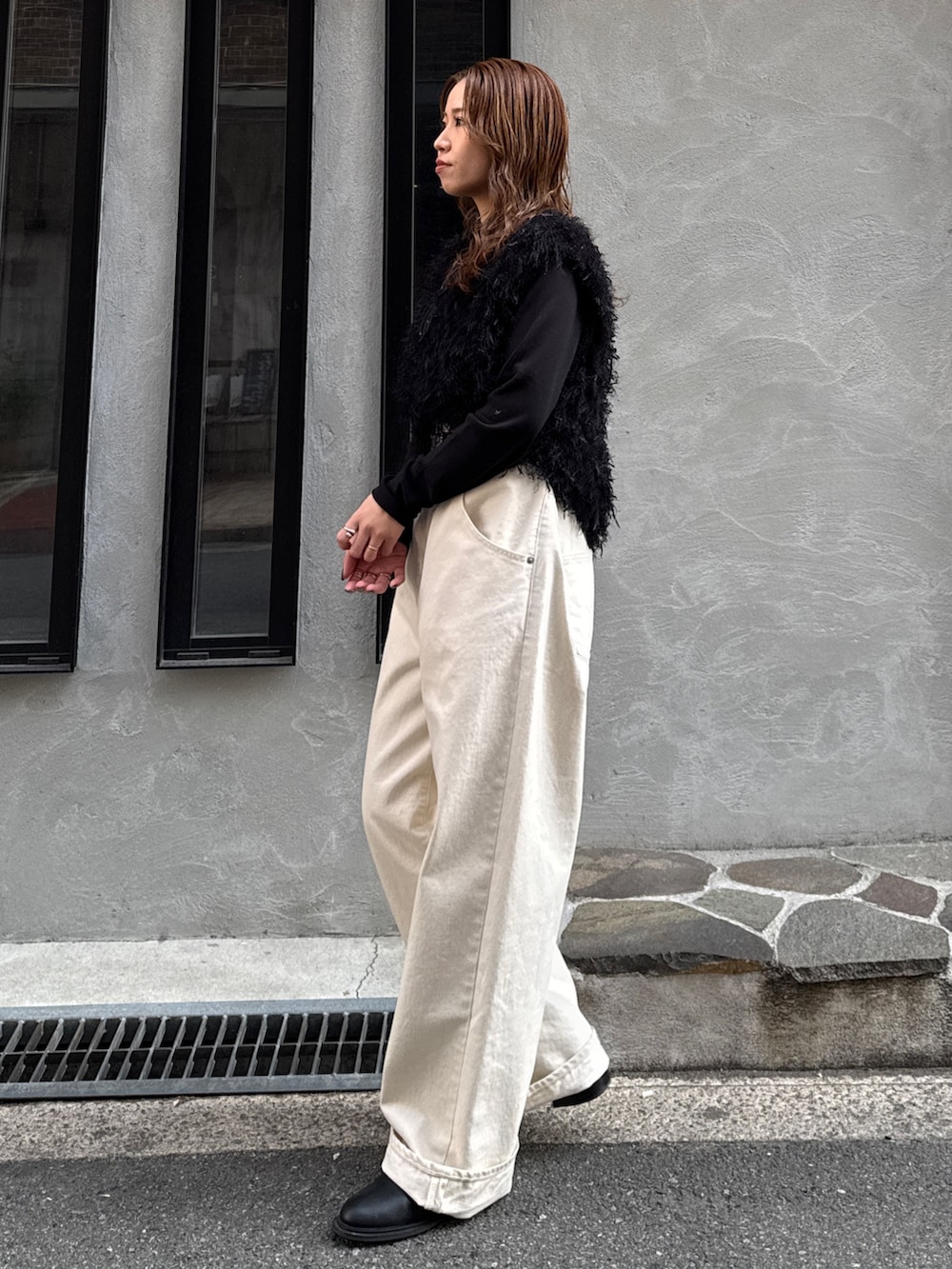 ホワイト系のデニムパンツ、ブラック系のニット/セーター、ブラック系のTシャツ/カットソーを着用したレディースの冬コーディネートの5枚目の写真