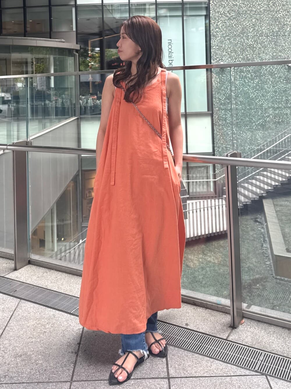 ブルー系のデニムパンツ、オレンジ系のワンピースを着用したレディースの春コーディネートの2枚目の写真