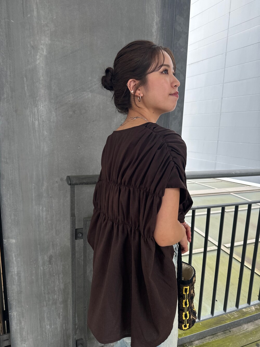 ブルー系のデニムパンツ、ホワイト系のサンダル、ブラウン系のハンドバッグを着用したレディースの夏コーディネートの4枚目の写真