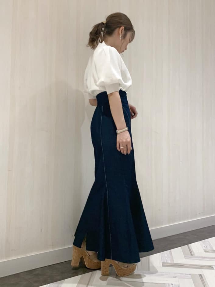 ブルー系のスカート、ホワイト系のニット/セーター、ベージュ系のサンダルを着用したレディースの春コーディネートの2枚目の写真