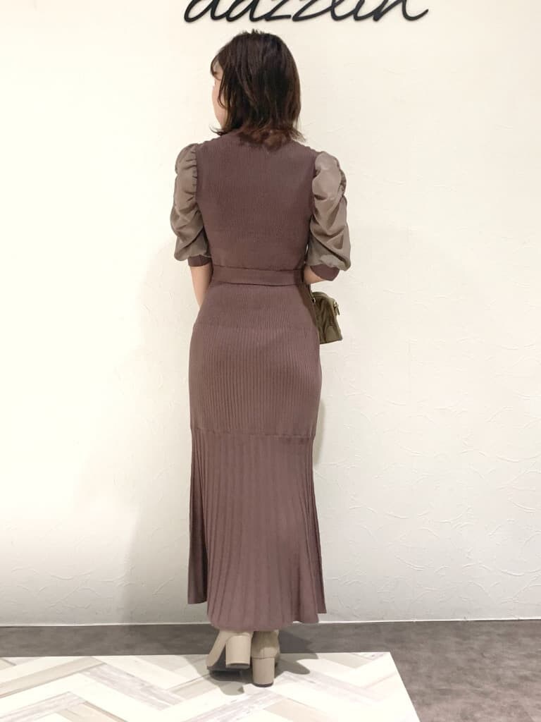 ブラウン系のワンピース、グレー系のトレンチコート、ベージュ系のハンドバッグを着用したレディースの秋コーディネートの3枚目の写真