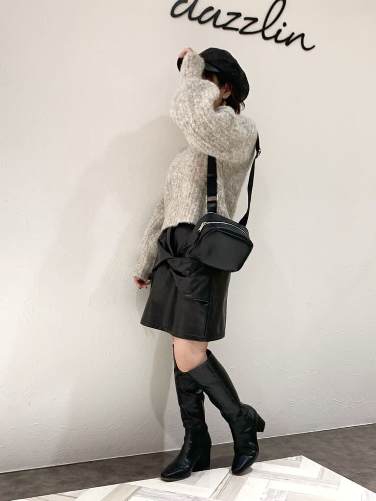 ブラック系のスカート、ブラック系のブーツ、ベージュ系のニット/セーターを着用したレディースの秋コーディネートの2枚目の写真