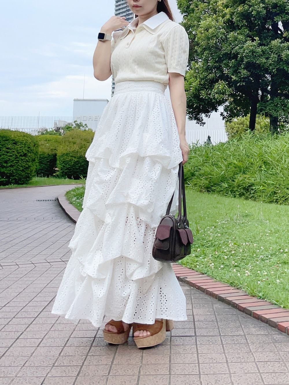 ホワイト系のニット/セーター、ホワイト系のスカート、ブラウン系のボストンバッグを着用したレディースの夏コーディネートの4枚目の写真