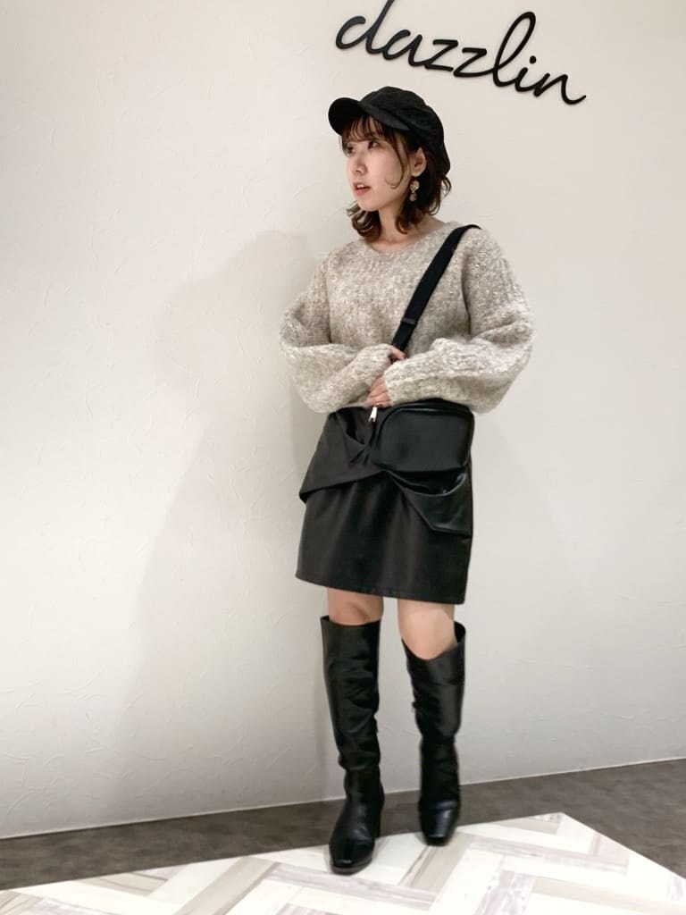 ブラック系のスカート、ブラック系のブーツ、ベージュ系のニット/セーターを着用したレディースの秋コーディネートの3枚目の写真