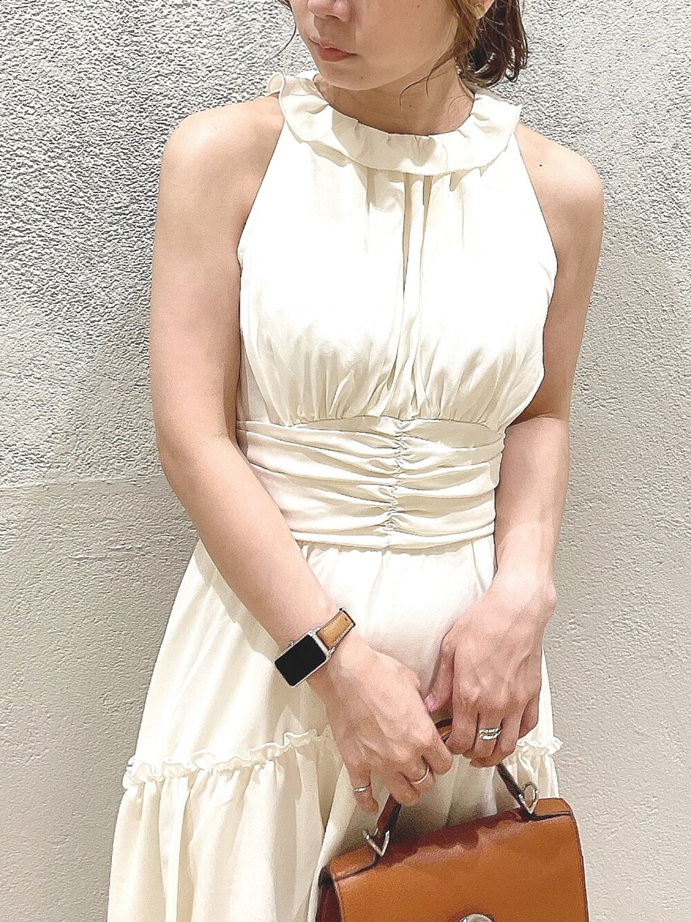 イエロー系のハンドバッグ、ホワイト系のサンダル、ホワイト系のワンピースを着用したレディースの夏コーディネートの6枚目の写真