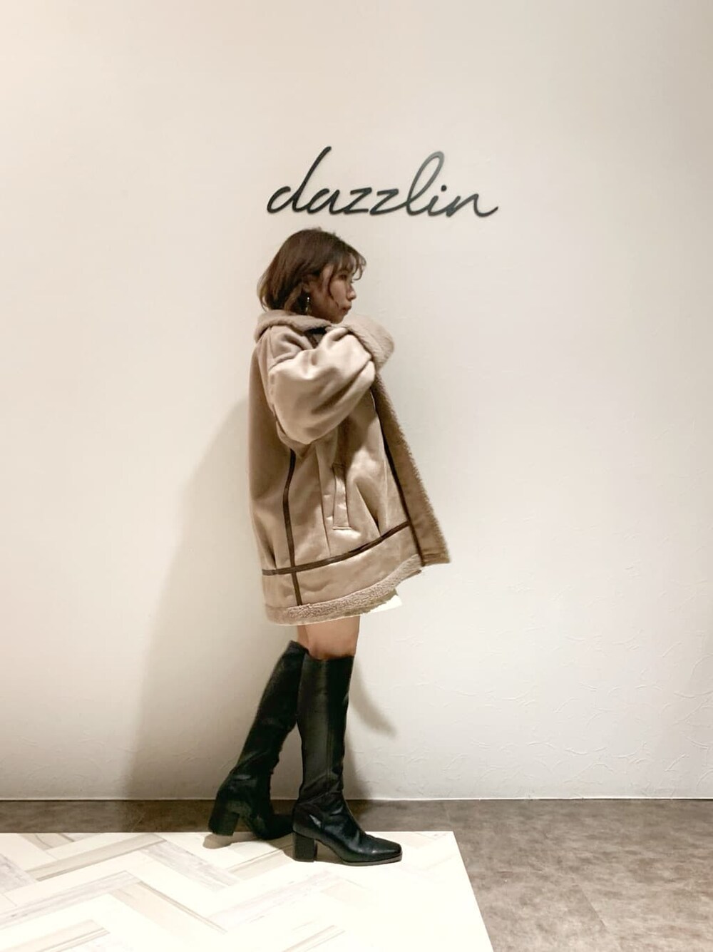 ベージュ系のブルゾン、ベージュ系のスカート、ブラック系のブーツを着用したレディースの秋コーディネートの3枚目の写真