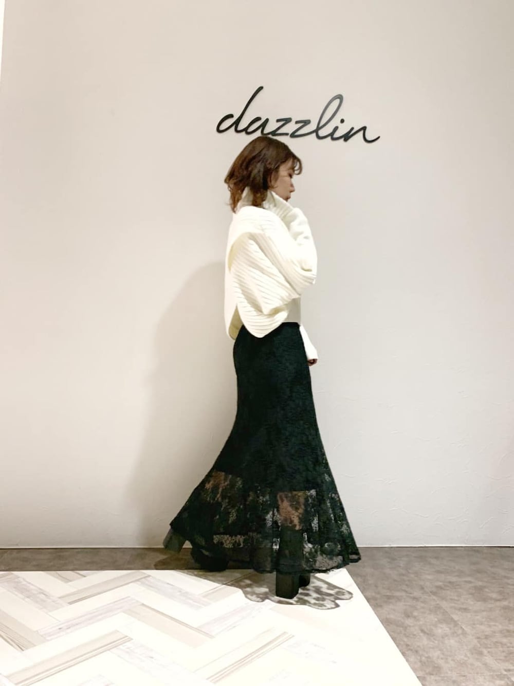 ブラック系のスカート、グレー系のブーツ、ホワイト系のニット/セーターを着用したレディースの秋コーディネートの3枚目の写真