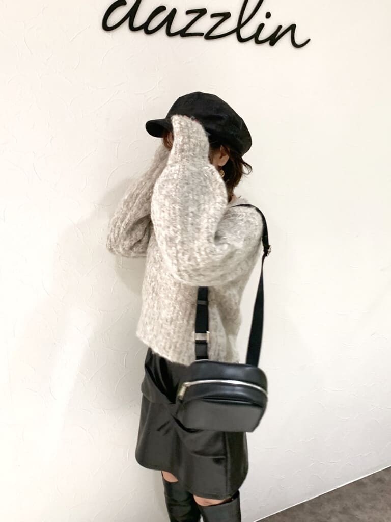 ブラック系のスカート、ブラック系のブーツ、ベージュ系のニット/セーターを着用したレディースの秋コーディネートの5枚目の写真