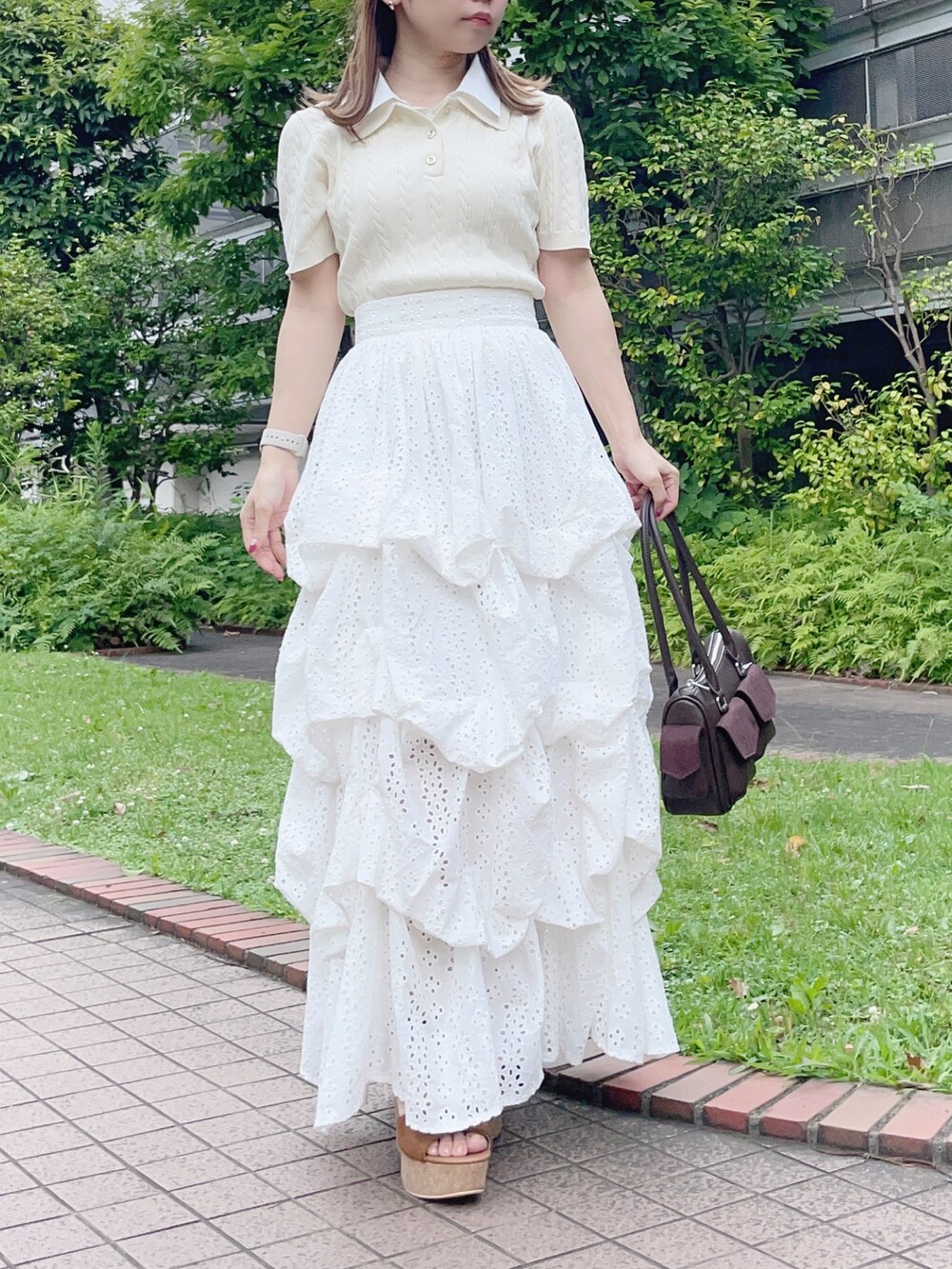 ホワイト系のニット/セーター、ホワイト系のスカート、ブラウン系のボストンバッグを着用したレディースの夏コーディネートの2枚目の写真