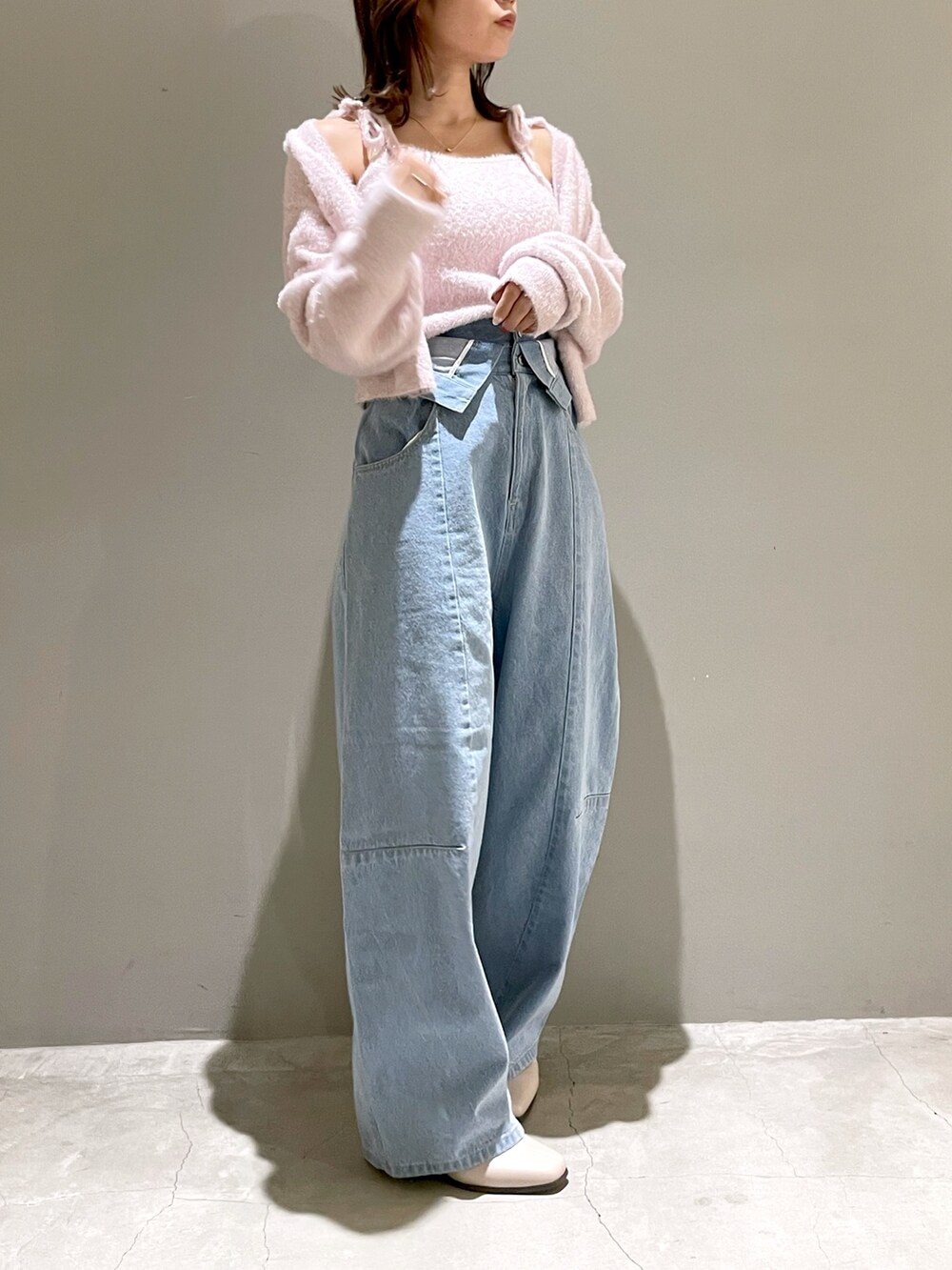 ピンク系のニット/セーター、ピンク系のカーディガン/ボレロ、ブルー系のデニムパンツを着用したレディースの秋コーディネートの2枚目の写真